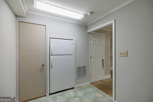 kitchen with freestanding refrigerator, visible vents, a textured ceiling, and ornamental molding