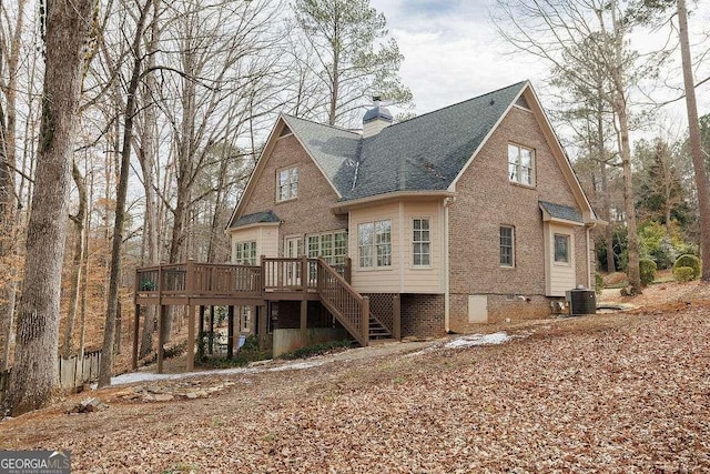 rear view of house featuring cooling unit, brick siding, stairway, a wooden deck, and a chimney