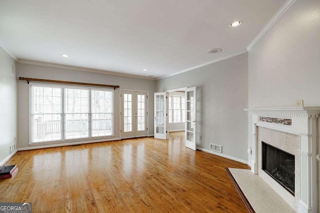 unfurnished living room with french doors, a wealth of natural light, visible vents, a premium fireplace, and wood finished floors