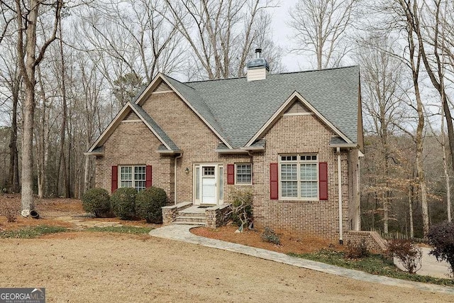 craftsman-style home with roof with shingles, brick siding, and a chimney