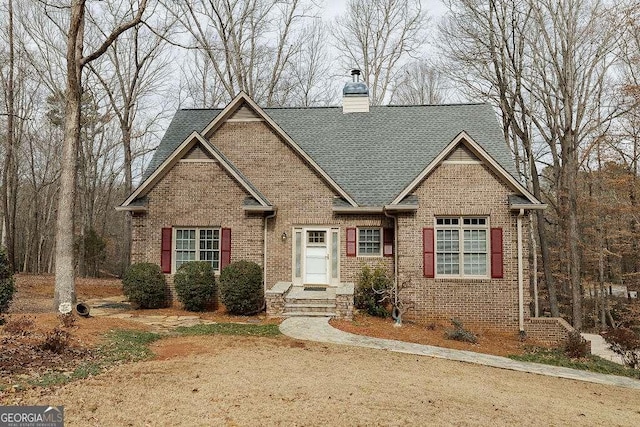 craftsman inspired home with roof with shingles, a chimney, and brick siding