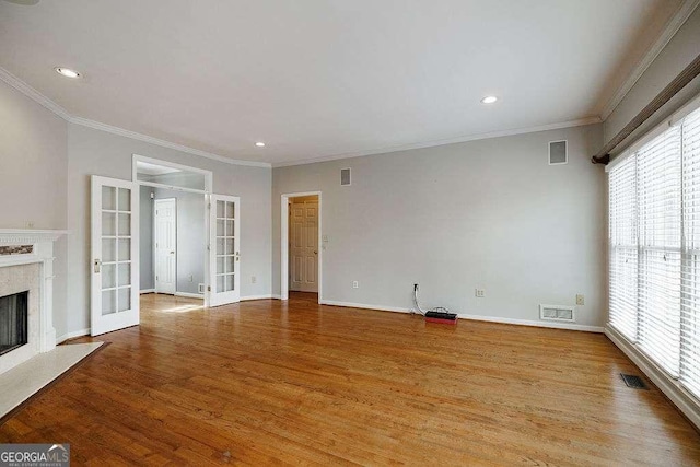 unfurnished living room featuring light wood-type flooring, french doors, visible vents, and a fireplace