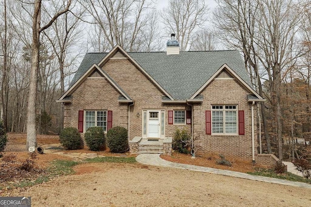 view of front of house featuring a chimney, brick siding, and roof with shingles