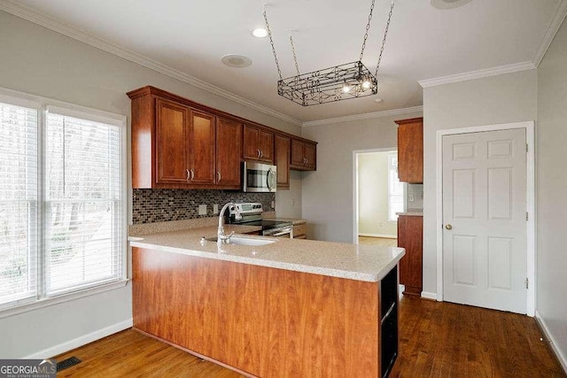kitchen with dark wood-style flooring, tasteful backsplash, light countertops, a peninsula, and appliances with stainless steel finishes