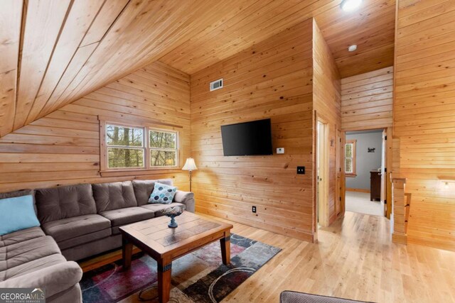 living area with vaulted ceiling, wood finished floors, wood ceiling, and wooden walls