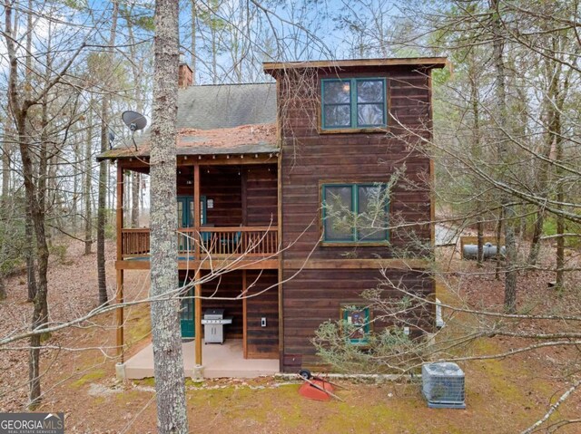 view of side of home featuring log veneer siding and driveway