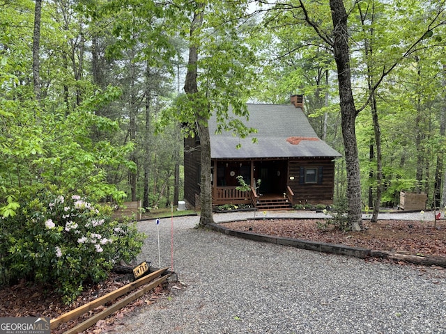 chalet / cabin with covered porch and a chimney