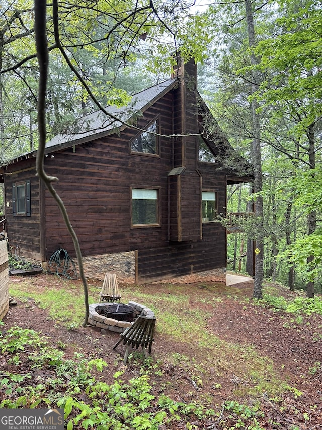 view of property exterior featuring a fire pit and a chimney