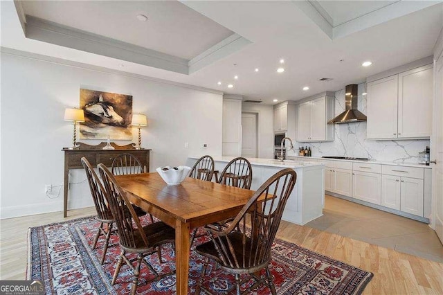 dining room featuring light wood-style floors, recessed lighting, a raised ceiling, and crown molding