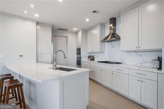 kitchen featuring gas stovetop, visible vents, a sink, oven, and wall chimney exhaust hood