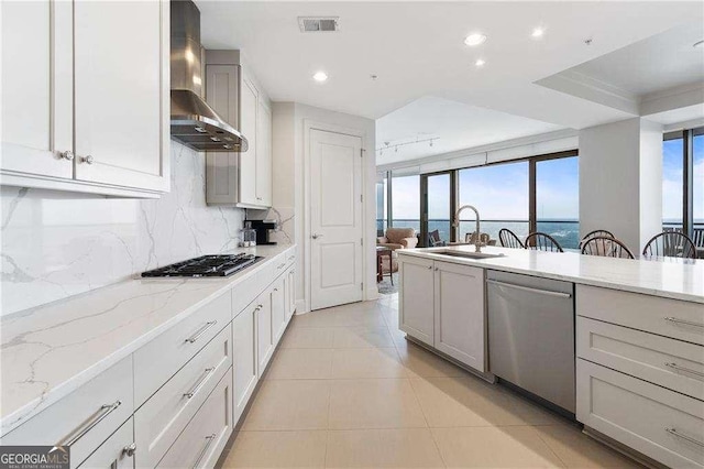 kitchen with wall chimney exhaust hood, backsplash, stainless steel dishwasher, gas stovetop, and a sink