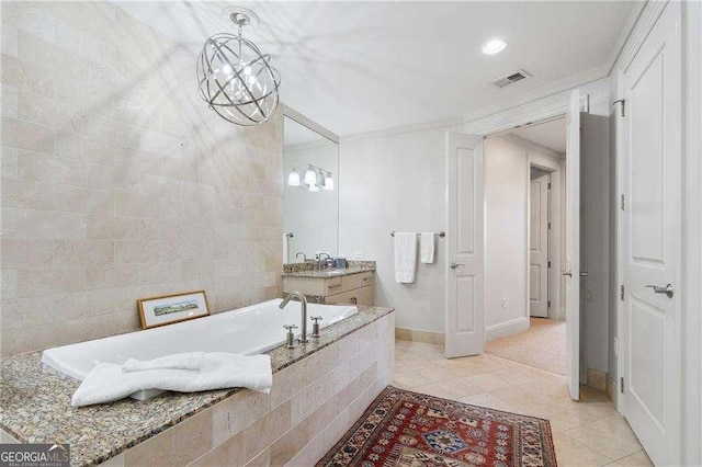 bathroom with a garden tub, vanity, baseboards, visible vents, and tile patterned floors