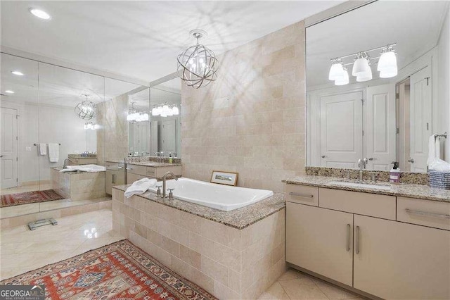 bathroom featuring a notable chandelier, a sink, tile walls, a bath, and tile patterned floors