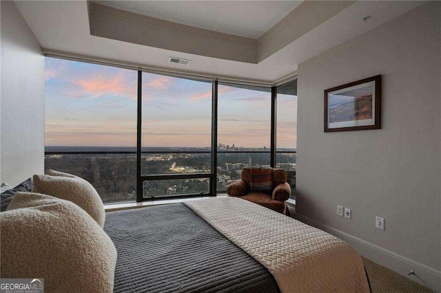 bedroom featuring baseboards, visible vents, a wall of windows, and a raised ceiling