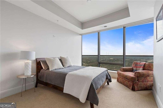 bedroom with crown molding, a raised ceiling, visible vents, a wall of windows, and baseboards