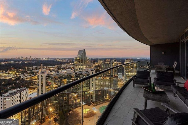 balcony at dusk featuring a view of city