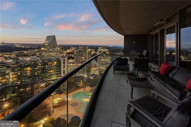 balcony at dusk with an outdoor hangout area and a city view