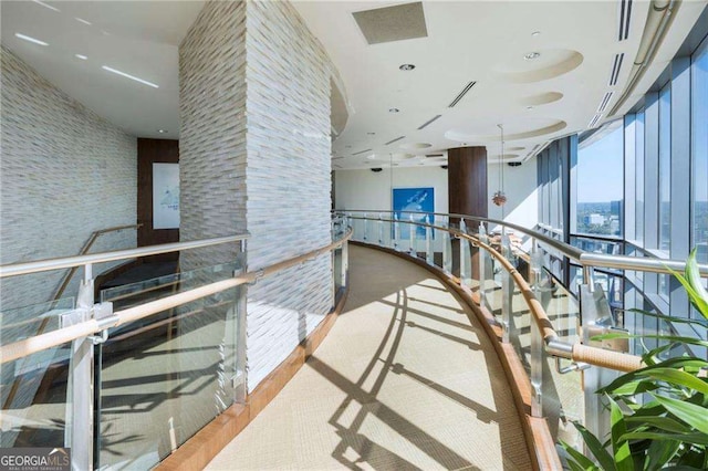 hallway featuring a wall of windows, wood finished floors, and an upstairs landing