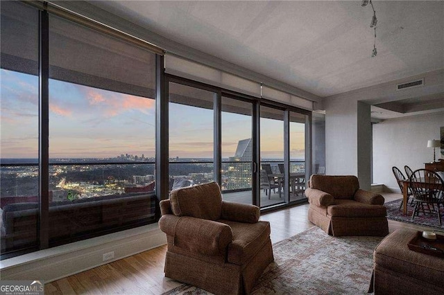 living area with expansive windows, wood finished floors, and visible vents