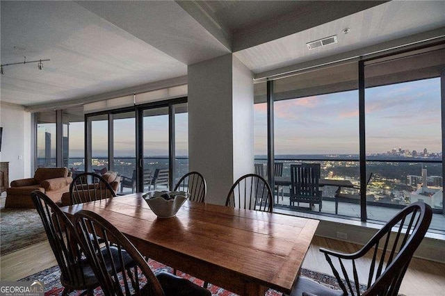 dining room featuring a wall of windows, a view of city, visible vents, and wood finished floors