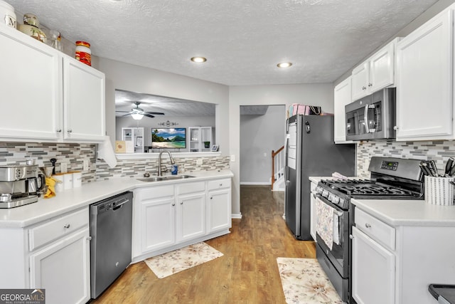 kitchen featuring a sink, white cabinets, light wood finished floors, and stainless steel appliances