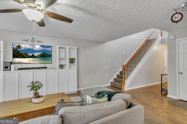 living area featuring stairway, baseboards, a textured ceiling, and wood finished floors