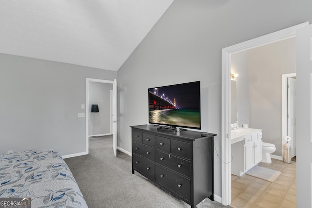 bedroom featuring a sink, baseboards, lofted ceiling, and ensuite bathroom