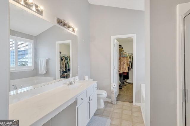 full bath featuring a spacious closet, baseboards, toilet, a garden tub, and vanity