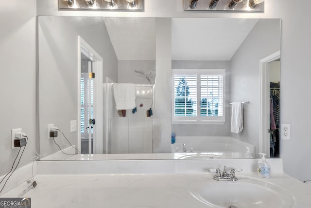 bathroom featuring a stall shower, a garden tub, and a sink