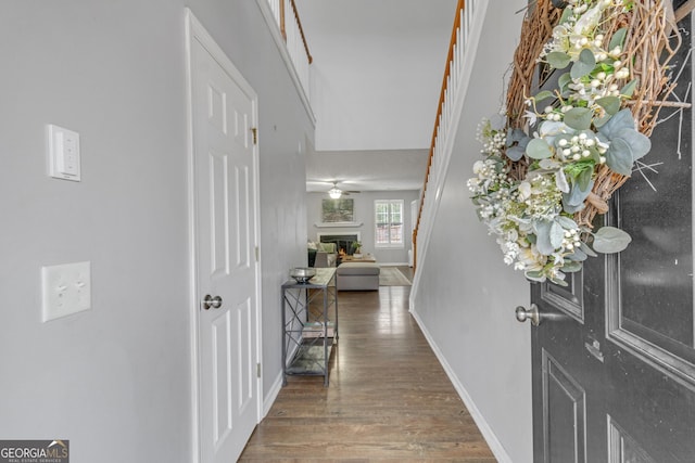 foyer entrance with baseboards, a lit fireplace, and wood finished floors