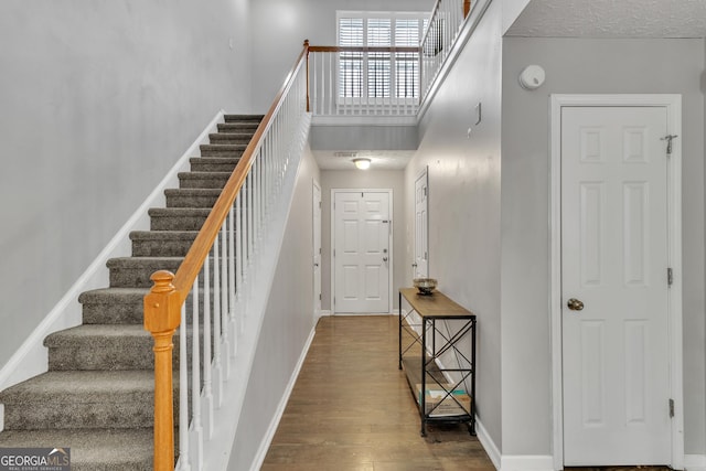 staircase featuring a high ceiling, wood finished floors, and baseboards