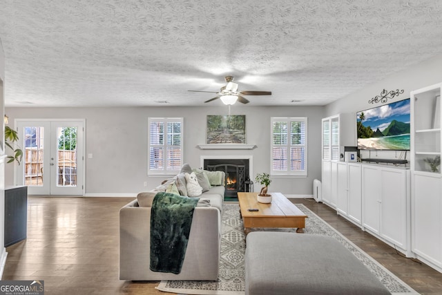 living area with dark wood finished floors, french doors, baseboards, and a lit fireplace