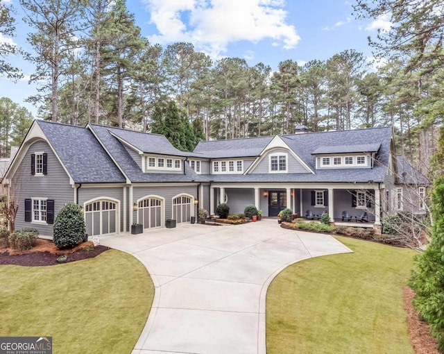 shingle-style home featuring covered porch, driveway, a front lawn, and a shingled roof