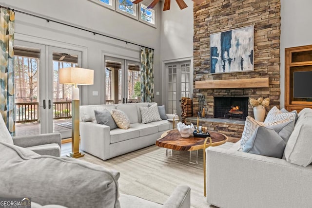 living room with ceiling fan, a stone fireplace, french doors, and plenty of natural light