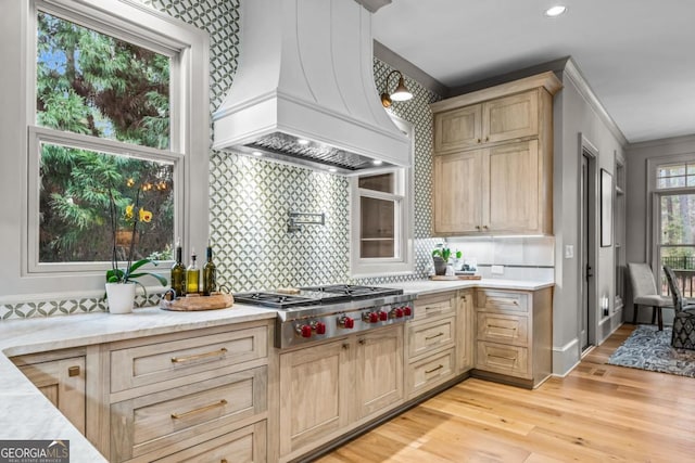 kitchen featuring stainless steel gas cooktop, custom exhaust hood, tasteful backsplash, light brown cabinetry, and light wood-style floors