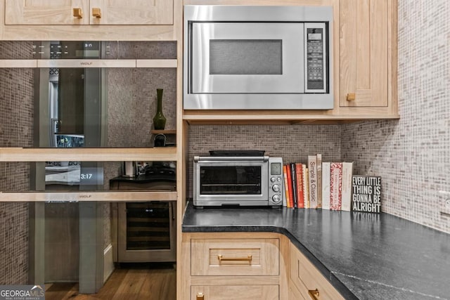 kitchen featuring a toaster, beverage cooler, tasteful backsplash, dark countertops, and stainless steel microwave