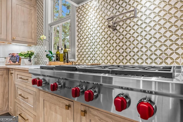 kitchen featuring light countertops, light brown cabinetry, backsplash, and stainless steel gas stovetop