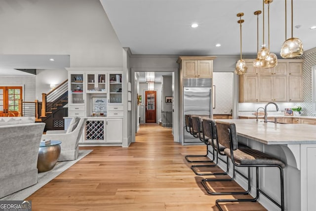 kitchen featuring a breakfast bar area, a sink, light wood-style floors, open floor plan, and stainless steel built in fridge