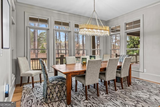 dining room with an inviting chandelier, crown molding, baseboards, and wood finished floors