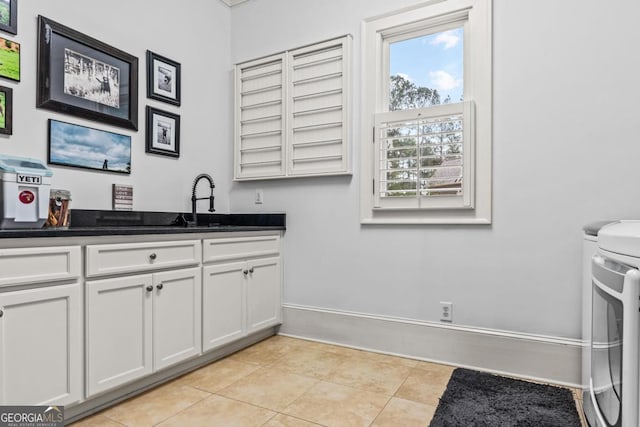 laundry area featuring cabinet space, light tile patterned flooring, a sink, independent washer and dryer, and baseboards