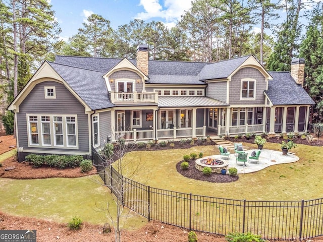 rear view of property with a fire pit, a patio, a sunroom, a chimney, and a yard