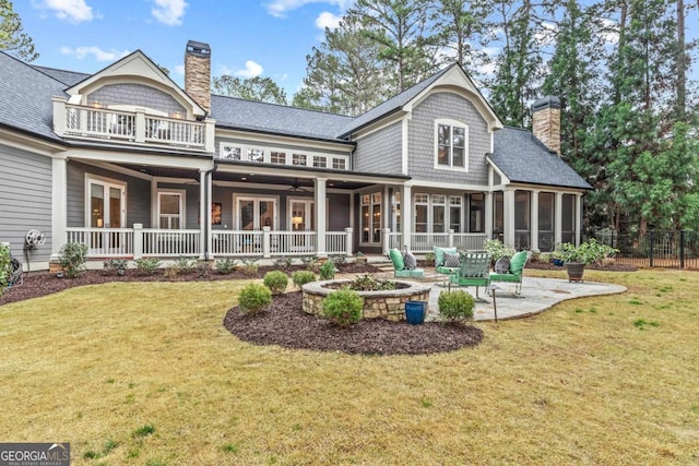 rear view of house featuring a sunroom, a yard, a chimney, and a balcony