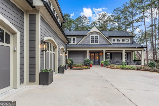 exterior space with a porch, roof with shingles, and driveway