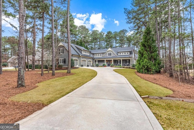 shingle-style home with concrete driveway and a front yard