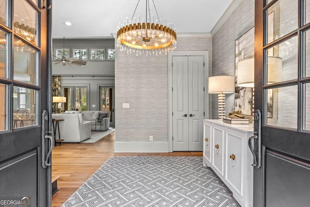 foyer featuring light wood finished floors, wallpapered walls, ceiling fan with notable chandelier, crown molding, and recessed lighting