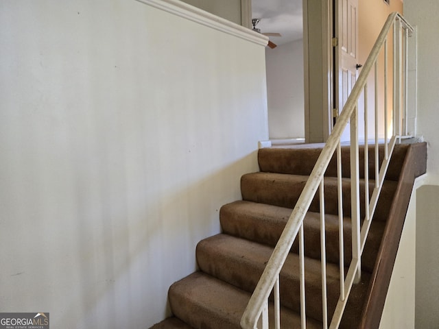 stairway featuring ceiling fan