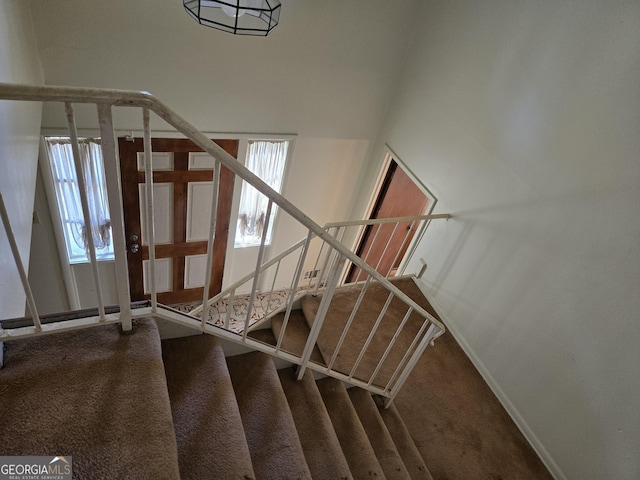 stairway with carpet floors, plenty of natural light, and baseboards