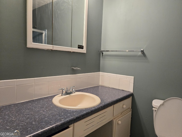 bathroom featuring tasteful backsplash, vanity, and toilet