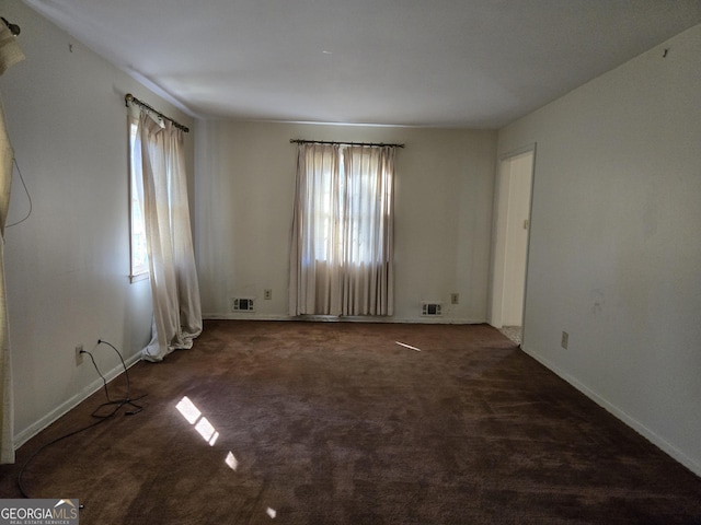 carpeted empty room featuring baseboards and visible vents