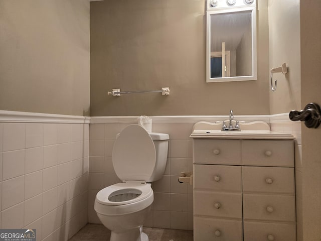 half bathroom with toilet, a wainscoted wall, and vanity